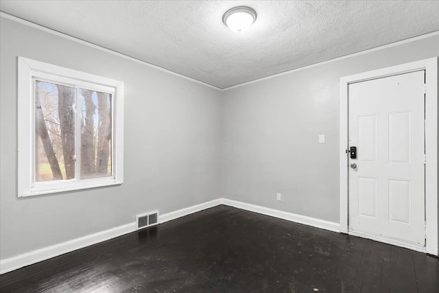 spare room featuring dark hardwood / wood-style floors, ornamental molding, and a textured ceiling