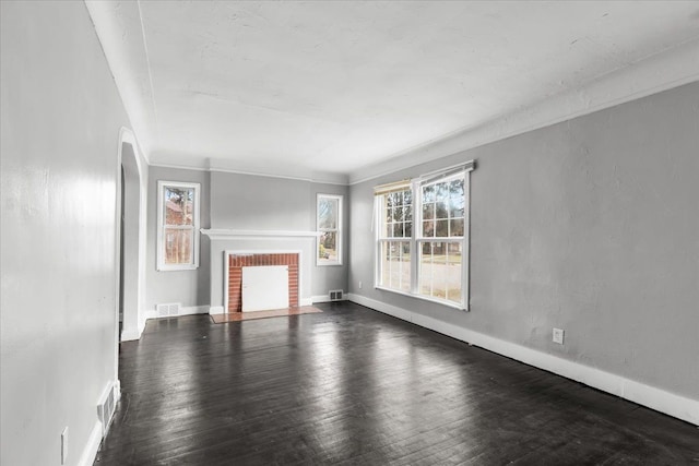 unfurnished living room with a fireplace, ornamental molding, and dark wood-type flooring