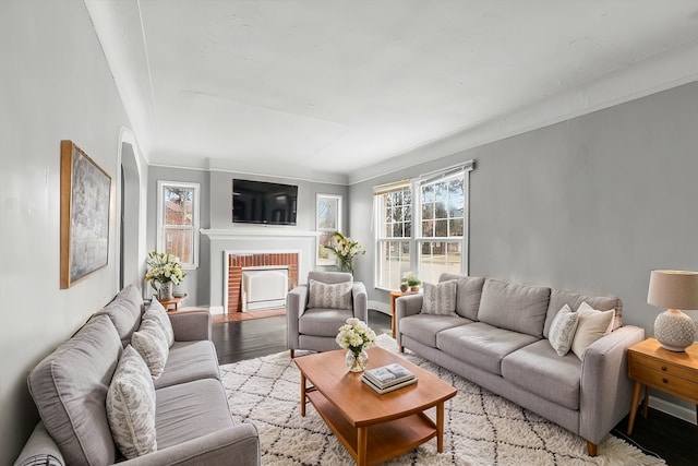 living room with a brick fireplace, light hardwood / wood-style flooring, and crown molding