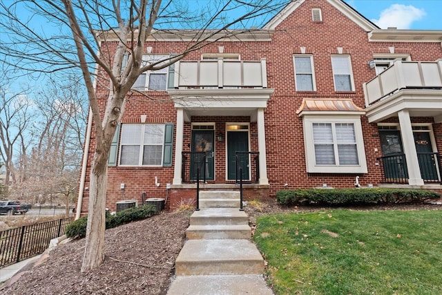 townhome / multi-family property featuring a balcony and a front lawn