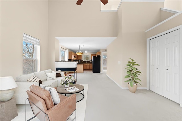 carpeted living room featuring ceiling fan and a high ceiling