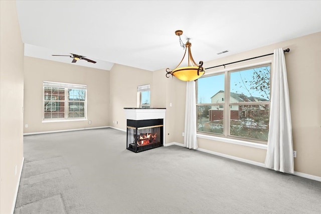 carpeted living room featuring ceiling fan, a multi sided fireplace, and a wealth of natural light