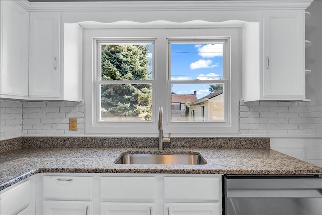 kitchen with decorative backsplash, stainless steel dishwasher, sink, stone countertops, and white cabinets