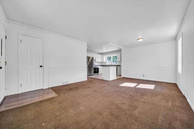 unfurnished living room with dark carpet, crown molding, and sink