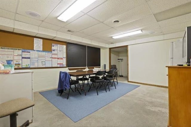 dining room with a paneled ceiling and concrete floors