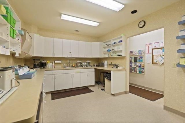 kitchen featuring white cabinets and light colored carpet