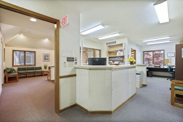 kitchen with kitchen peninsula, white cabinets, and light colored carpet