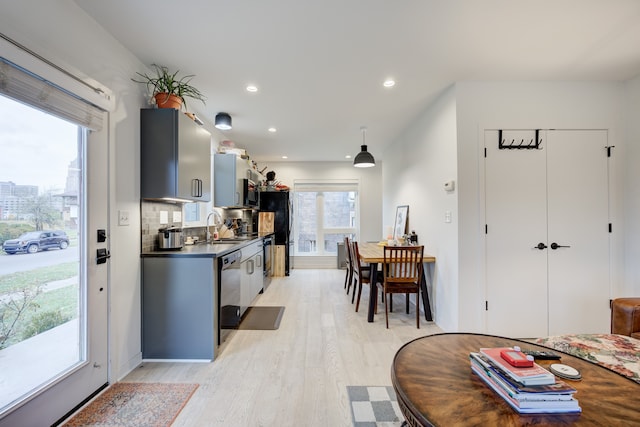 kitchen featuring pendant lighting, backsplash, sink, light hardwood / wood-style floors, and stainless steel appliances