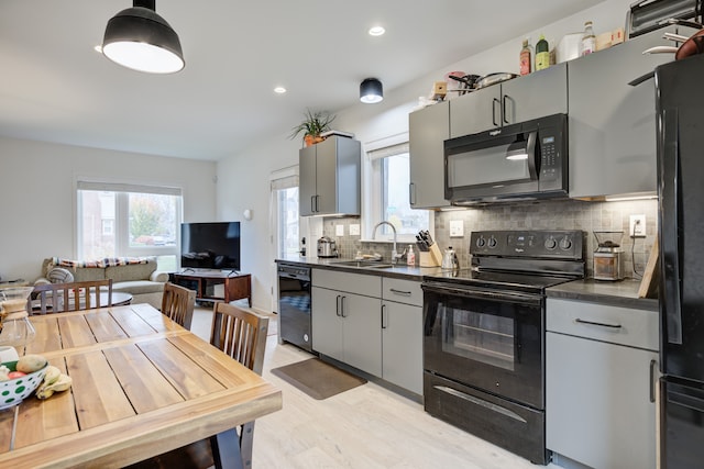 kitchen with gray cabinetry, black appliances, sink, light hardwood / wood-style flooring, and tasteful backsplash