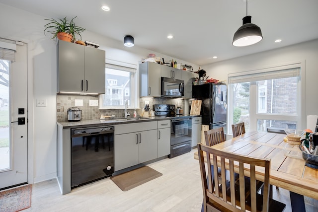 kitchen featuring tasteful backsplash, sink, black appliances, pendant lighting, and gray cabinets