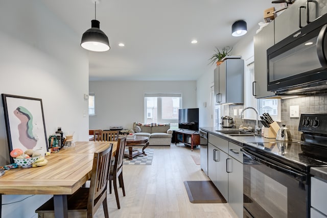 kitchen featuring sink, tasteful backsplash, light hardwood / wood-style floors, gray cabinets, and black appliances