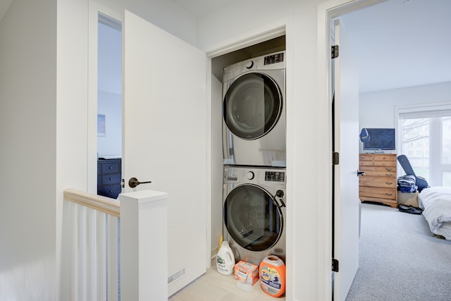 clothes washing area with light colored carpet and stacked washing maching and dryer