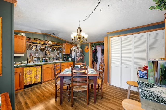 dining room featuring a textured ceiling, dark wood-type flooring, lofted ceiling, and a notable chandelier