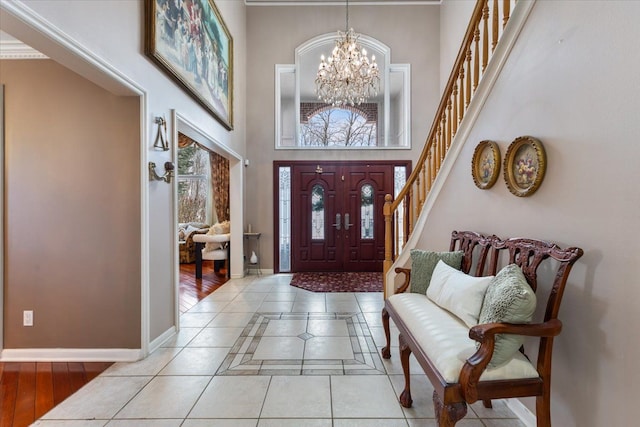 foyer featuring a high ceiling, a notable chandelier, and light tile patterned flooring