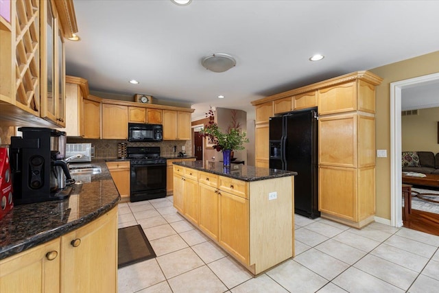 kitchen featuring black appliances, a center island, light tile patterned floors, and dark stone counters