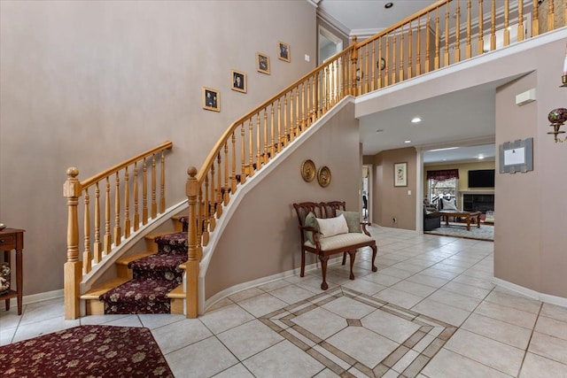 staircase with tile patterned floors, a towering ceiling, and a tile fireplace