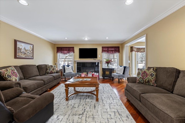 living room featuring hardwood / wood-style flooring, crown molding, and a tiled fireplace