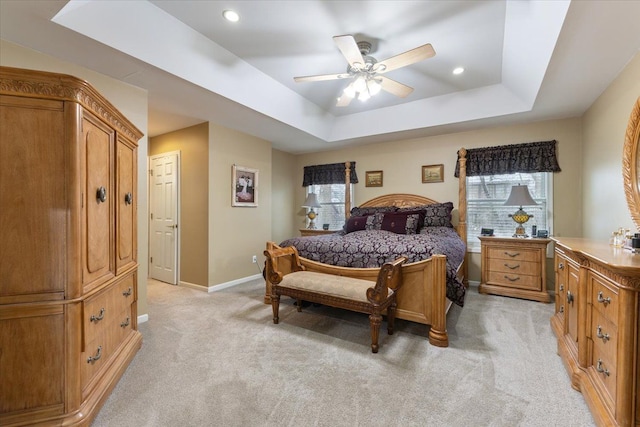 carpeted bedroom featuring ceiling fan, a closet, multiple windows, and a tray ceiling