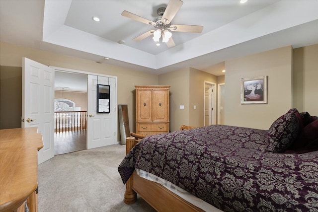 bedroom with ceiling fan, a raised ceiling, and light carpet