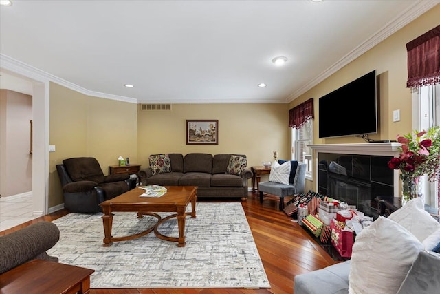 living room with a tile fireplace, ornamental molding, and hardwood / wood-style flooring