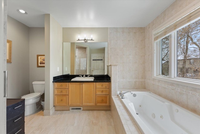 bathroom with tile patterned flooring, vanity, toilet, and tiled bath