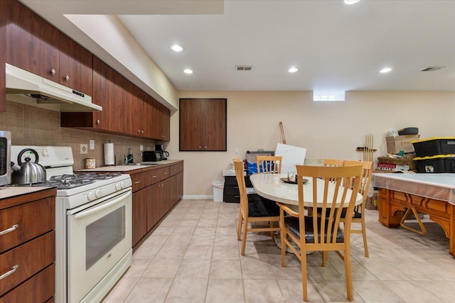 kitchen with decorative backsplash, light tile patterned floors, and gas range gas stove