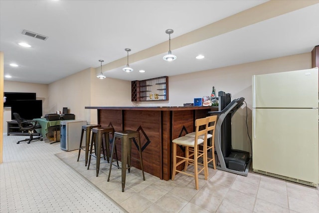 bar featuring white fridge and hanging light fixtures