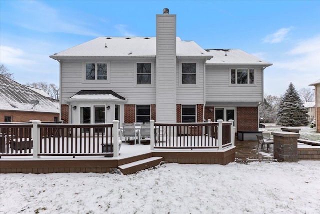 snow covered back of property with a deck