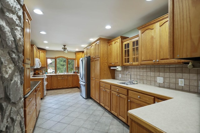 kitchen featuring stainless steel refrigerator, ceiling fan, sink, range with electric stovetop, and decorative backsplash