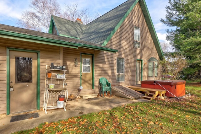 back of property with a hot tub and a lawn