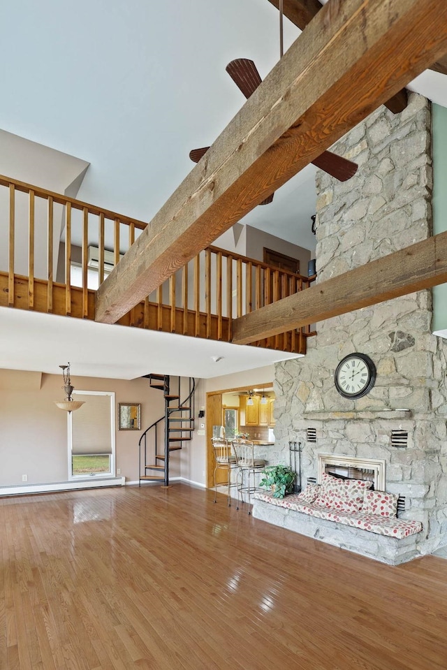 unfurnished living room with wood-type flooring, a fireplace, and a towering ceiling