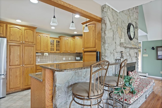 kitchen featuring tasteful backsplash, dark stone counters, decorative light fixtures, a breakfast bar, and a kitchen island