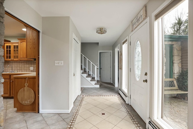 tiled entrance foyer with sink and a baseboard heating unit