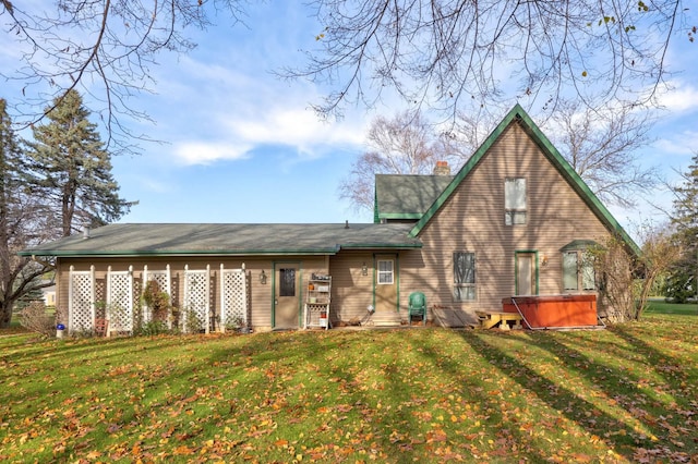 back of property with a yard and a hot tub