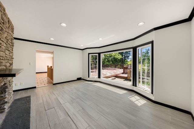 unfurnished living room featuring a fireplace, ornamental molding, a healthy amount of sunlight, and light wood-type flooring