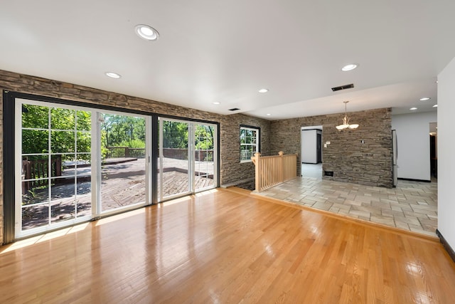 unfurnished living room with light hardwood / wood-style flooring and a notable chandelier