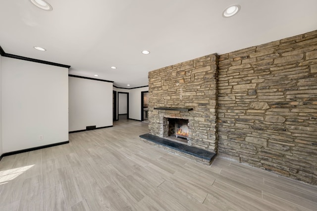 unfurnished living room with light hardwood / wood-style floors, a stone fireplace, and ornamental molding