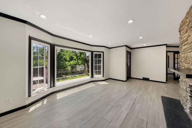 unfurnished living room featuring crown molding, plenty of natural light, and light hardwood / wood-style floors