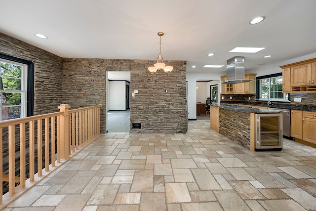 kitchen featuring dark stone counters, hanging light fixtures, tasteful backsplash, island exhaust hood, and a chandelier