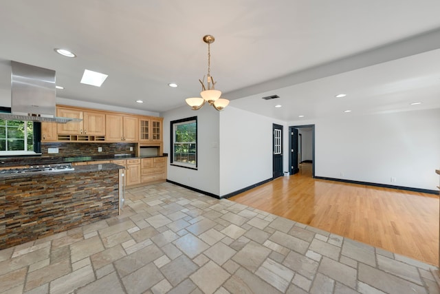 kitchen with island exhaust hood, light brown cabinetry, tasteful backsplash, light hardwood / wood-style flooring, and stainless steel gas stovetop