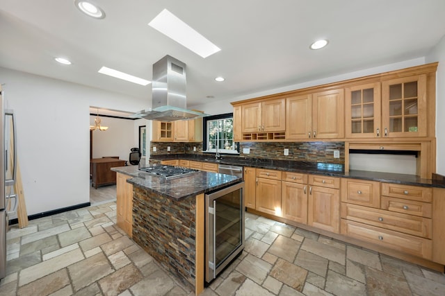 kitchen featuring a center island, wine cooler, decorative backsplash, dark stone counters, and island range hood