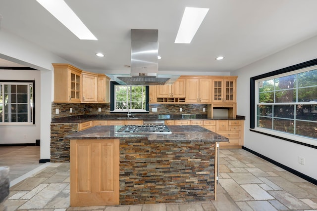 kitchen featuring decorative backsplash, island range hood, a kitchen island, and stainless steel gas cooktop