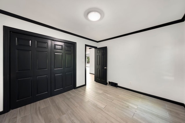 unfurnished bedroom with light hardwood / wood-style flooring, a closet, and crown molding