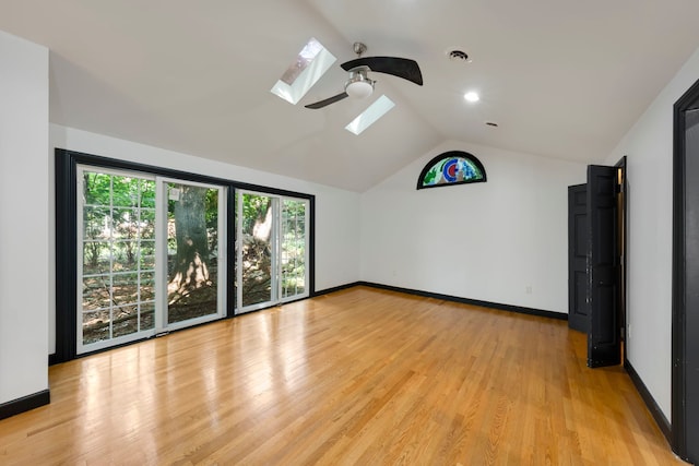 unfurnished room featuring ceiling fan, plenty of natural light, light hardwood / wood-style floors, and vaulted ceiling with skylight