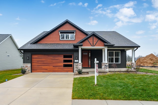 craftsman-style house with driveway, covered porch, stone siding, and board and batten siding