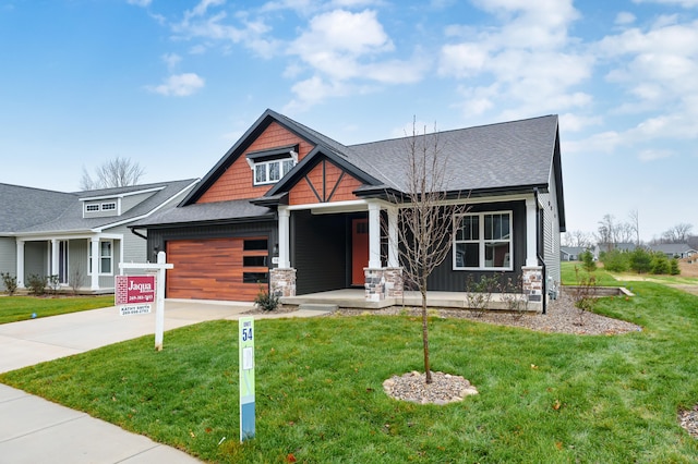 craftsman inspired home with covered porch, a front yard, and a garage