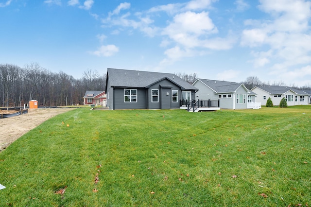 back of house with a deck, a lawn, and a residential view