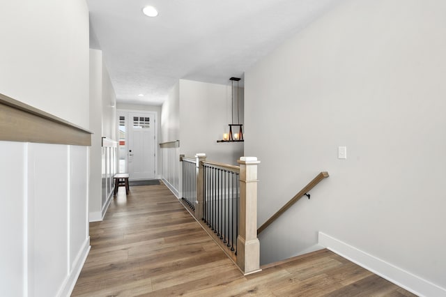 hallway with recessed lighting, baseboards, wood finished floors, and an upstairs landing