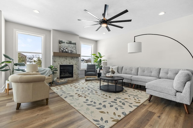 living area with recessed lighting, wood finished floors, and a glass covered fireplace