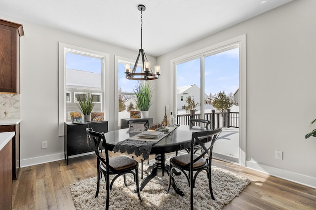 dining area with wood finished floors, baseboards, and an inviting chandelier